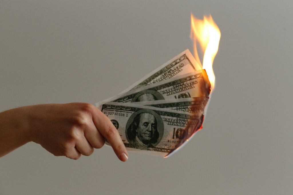 woman holding a burning dollar bills